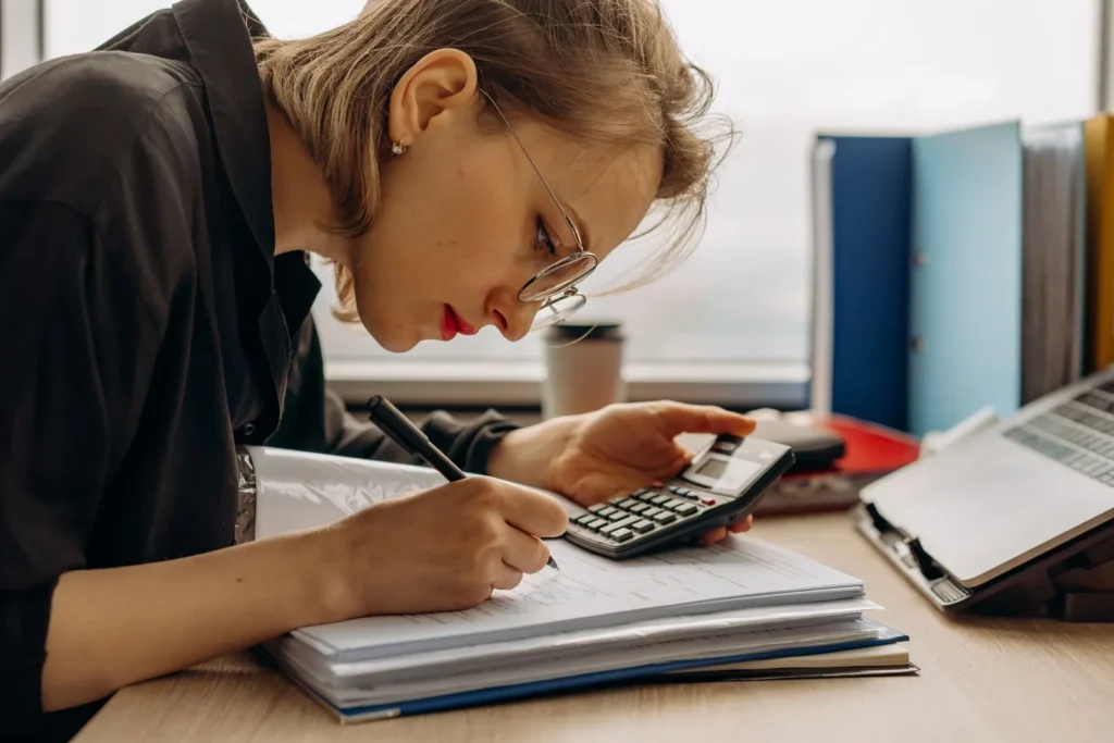 Accountant writing notes while using a calculator
