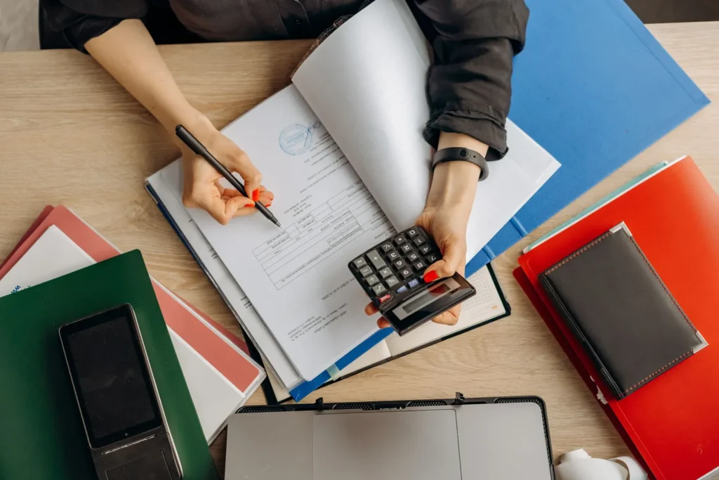 Overhead view of an accountant working through documents with a calculator