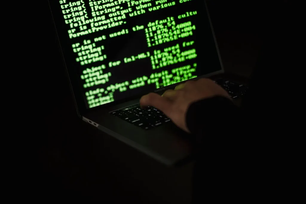 Person typing on a laptop with lines of code on screen