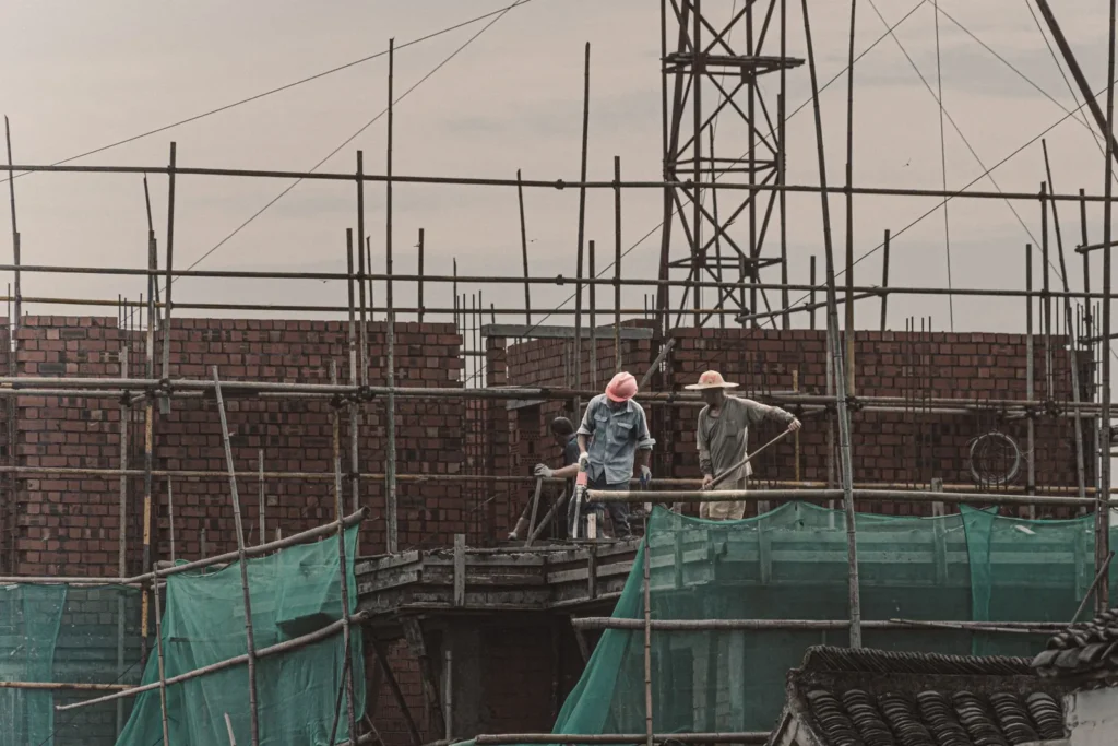 Construction crew working on scaffolding against a brick wall