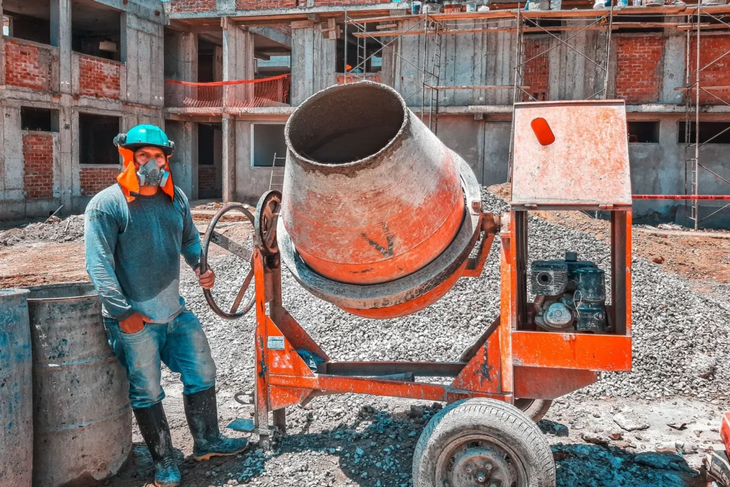 Site worker beside a concrete mixer on a construction site